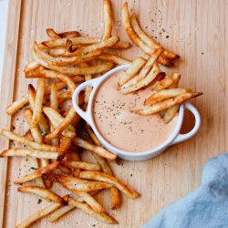 French fries on a cutting board with truffle fry and burger sauce