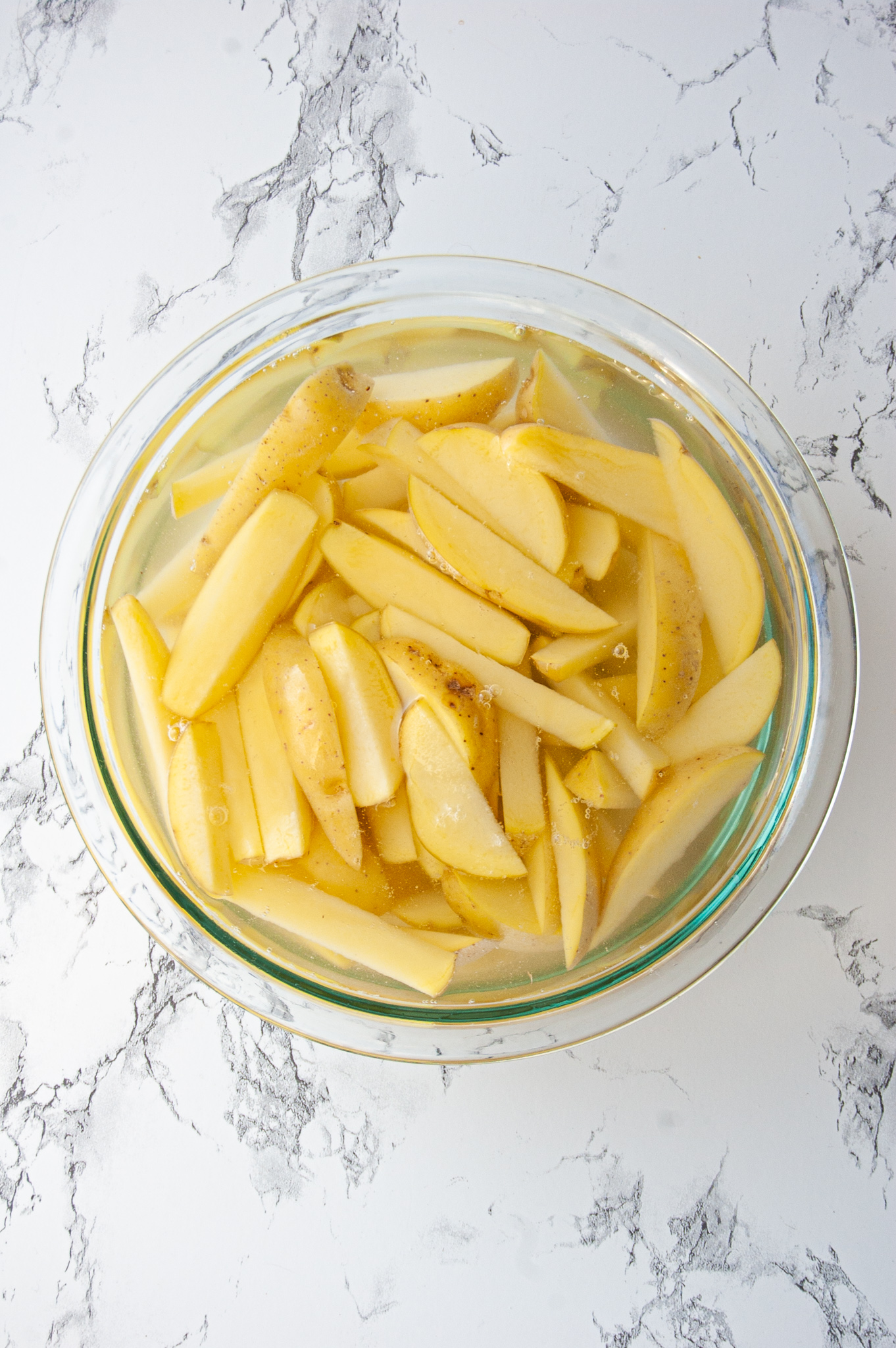 Sliced potatoes soaking in a bowl of water for french fries